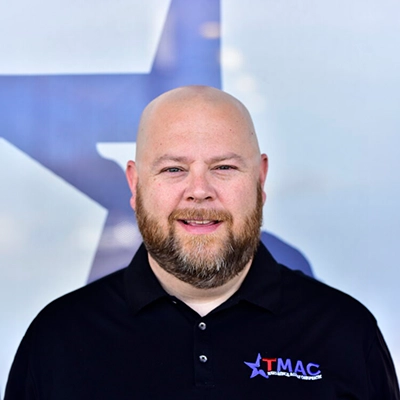 Insurance and Financial Solutions Director Brint Richter Smiling In Front Of Logo Backdrop
