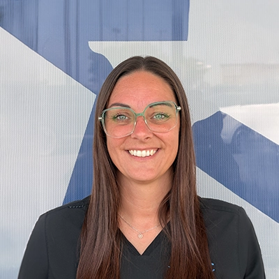 Chiropractic Assistant Brittany Honeycutt Smiling In Front Of Logo Backdrop