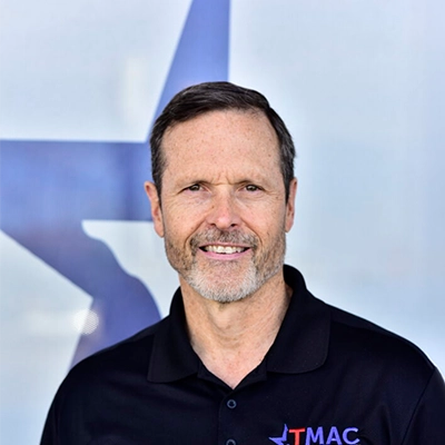 Family Nurse Practitioner Eric Williams Smiling In Front Of Logo Backdrop