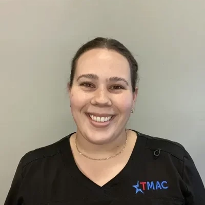 Rehab Tech Hannah Todd Smiling In Front Of Tan Backdrop