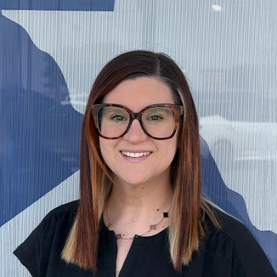 Chiropractic Assistant Kayla Gibbs Smiling In Front Of Logo Backdrop