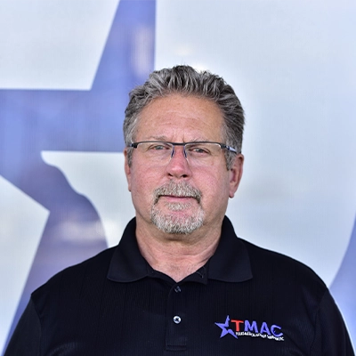 Chiropractor Stewart Chapman Smiling In Front Of Logo Backdrop